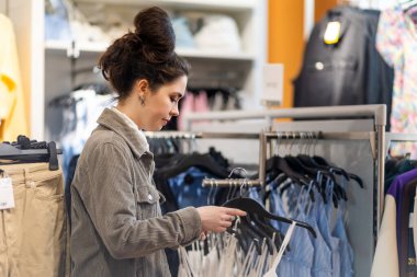 Genç kadın seçimlerinin yan görünüşü mağazada giyinmek. Kara Cuma ve tüketim kavramı.