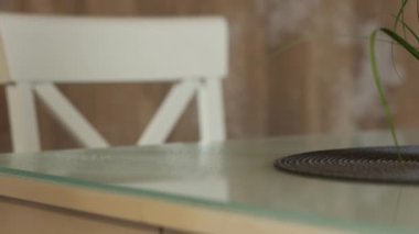 Lastik eldivenli ev sahibi, deterjanı masaya püskürtür ve bezle siler. Ellerinizi yakın tutun. Temizlik ve angarya işleri kavramı.