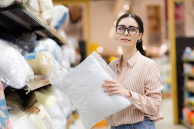 Beyaz tenli, gözlüklü, yastıklı güzel bir kadının portresi. Süpermarkette ev yapımı tekstil. Alışveriş konsepti.