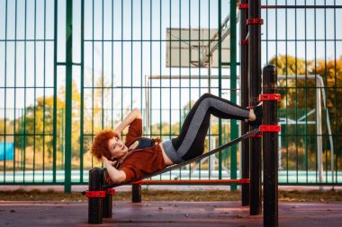 Beyaz, orta yaşlı bir kadının karın kasılmaları yaşaması şehir parkındaki yedek kulübesinde yatıyor. Uzayı kopyala Spor ve spor anlayışı.