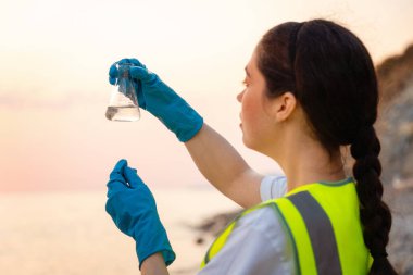 Dünya günü. Çevre bilimci, denizden gelen kimyasal numune şişesini inceliyor. Çevre kirliliği ve ekoloji kavramı.