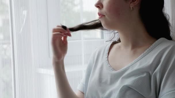 Zaniepokojona Biała Kobieta Lokuje Kosmyk Włosów Palcu Patrzy Okno Strzał — Wideo stockowe