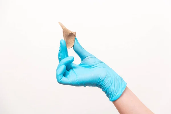 Podiatrist in blue gloves show a silicone impression for correction ingrown nails on toe fingers. Close-up. The concept of podology and chiropody.