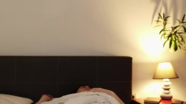 Korkak beyaz kadın korkunç bir kabustan dolayı yatakta uyanıyor. Duygusal stres ve uykusuzluk kavramı.