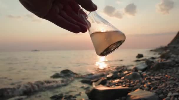 Närbild Glasprovkolv Smutsigt Vatten Undersöks Ekolog Solnedgång Och Hav Bakgrunden — Stockvideo
