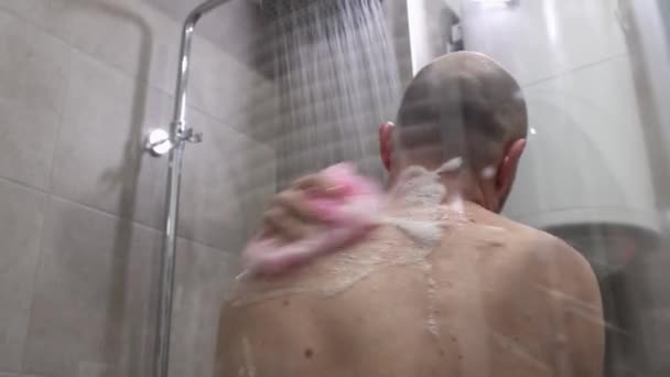 若いハゲ白人男性のバックビューは泡立つスポンジでシャワーを取ります クローズアップビュー 日々の衛生 — ストック動画