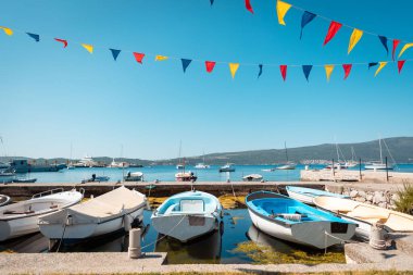 Akdeniz kıyısında tekneleri ve bayrakları olan güzel güneşli bir köy iskelesi manzarası. Tatil köylerinde yaz tatili.