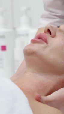 Profesyonel kozmetik uzmanına yakın çekim müşterinin kadınına gençleştirici masaj yapıyor. Ağır çekim. Cilt bakımı ve kozmetoloji