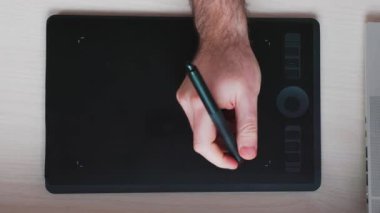 Erkek eli, Stylus 'u tablet çizerken tutuyor. Üst Manzara. Dijital illüstrasyon ve rötuş kavramı