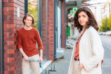 Bulanık genç beyaz adam gülümsüyor ve yoldan geçen güzel genç bayana bakıyor ve kameraya bakıyor. İlişkinin psikolojisi.