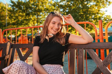 Yaz tatili. Güzel bir genç kadının portresi bir parkta oturuyor, mutlu bir şekilde gülümsüyor. Güneşli. Pozitif ifade ve duygu kavramı.