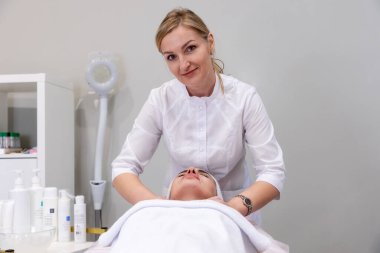 Profesyonel kozmetik uzmanı kadınlar için yüz gençleştirme masajı yapıyor. Salon yaşlanmayı önleme prosedürleri.