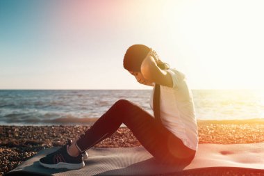 Spor anlayışı ve sağlıklı yaşam tarzı. Spor giyimli bir kadın Mat 'te ısınma turuna çıktı. Arka planda, deniz ve gökyüzü. Boşluğu kopyala.