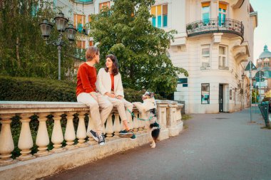 Saf köpek Avustralyalı genç beyaz bir çift kaldırımda oturuyor. Hayvan eğitimi ve şehir yürüyüşü..