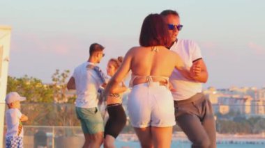 10.08.2024, İbiza, İspanya. Romantik Kafkasyalı kadın ve trenler bulvarda bir dans dersinde. Spor ve eğlence aktiviteleri. Sokak dansçıları tango gösterisi yapıyor.