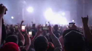 Müzik konserindeki insanlar grubun performansını akıllı telefonlarıyla kaydediyorlar. Kulüp atmosferi, kırmızı ışık huzmeleri ve telefonla el kaldırmalar. Dikiz aynası. Eğlence konsepti.