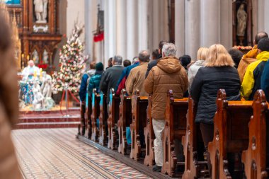 Church altar during Christmas Mass with The Nativity scene. Back view of standing parishioners. The Catholic Orthodox Christmas holiday in Europe. clipart