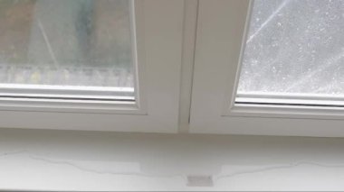 Pencerenin kenarına su sızdıran bir çerçeve, pencere kenarında bir su birikintisi. Yağmurlu bir hava. Üst görünüm.