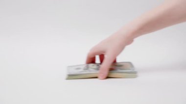 Rüşvet ve borsa. Amerikan doları masanın üzerinde yuvarlandı ve kadının eli parayı kaptı. Yakın plan. Beyaz arka plan. Yatırım, bankacılık ve finans kavramı