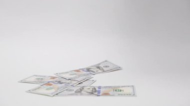 Nakit ve vergiler. Amerikan dolarlarının banknotları tepeden beyaz arka plana doğru yağar. Zenginlik ve yatırım kavramı.