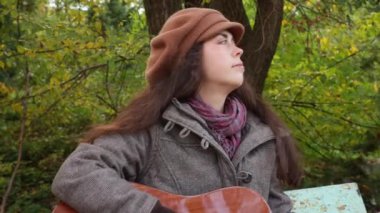 Parkta güzel beyaz bir kadının portresi gitar çalıyor. Orta boy. Müzik aletleri çalmayı öğrenmek.