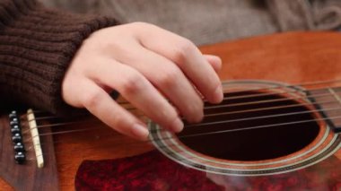 Gitar çalan bir kadının alt görüntüsü. Ellerinizi yakın tutun. Parkta müzik aletleri çalmayı öğrenmek.
