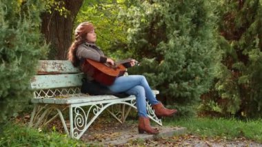 Kafkasyalı güzel bir kadın parkta gitarıyla bankta oturuyor. Düşük ihtimal. Müzik aletleri çalmayı öğrenmek.