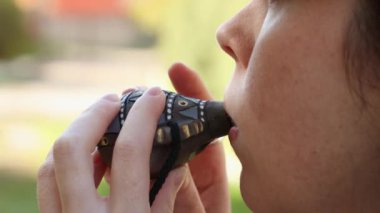 Okarina seramik flüt çalan beyaz bir kadının yüzünü kapatın. Yan görüş. Islık çalan bir oyuncağın etnik müziği.