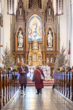 Yaşlı bir kadının mihraptan aşağı inişi ve genç bir adamın Noel ayini sırasında geri dönüşü. Avrupa 'daki Katolik Ortodoks Noel tatili. Dikey oryantal.
