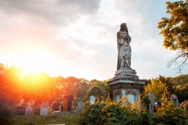 Günbatımında sonbahar mezarlığı. Mezar taşındaki melek heykelinin görüntüsü. Gözlerden uzak bir atmosfer. Boşluğu kopyala.
