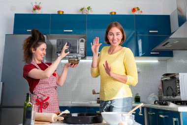 İki kadın mutfakta yemek pişirip birbirlerine un atıyorlar. Kapalı alanda. LGBT çiftleri ve eğlence kavramı.