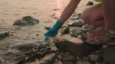 Gönüllü çevrecilerin deniz kıyısına yaklaşımlarını yakından inceler ve analiz için test tüpünde su toplar. Çevre kirliliği. Ekolojinin korunması ve kaynakların geri dönüşümü kavramı.