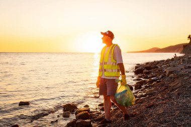 Lastik eldivenli gönüllü adam, çakıl taşlı kumsalı temizliyor. Uzayı kopyala Okyanus kirliliği kavramı ve çevreyi kurtarmak.