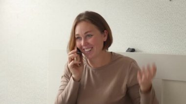 Genç beyaz bir kadının akıllı telefondan gülümseyen mutlu bir görüntüsü. Modern iletişim ve sosyal medya kavramı.