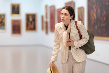 Orta yaşlı beyaz bir kadın, çağdaş bir sanat sergisini ziyaret ederken stres ve mide bulantısı yaşıyor. Müze Günü konsepti.