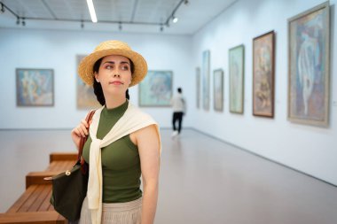 Sanat galerisinde saman şapkalı zarif beyaz bir kadının poz verişi. Uzayı kopyala Kültür Eğitimi ve Müze Günü kavramı.
