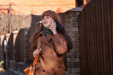 Dişlerinde diş teli olan beyaz bir kadın, sokakta dikilirken palto ve şapka takıyor. Yaşam tarzı ve şehir hayatı.