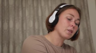 Kafkasyalı genç bir kadının portresi. Kulaklıklı, müzik dinleyen ve odasında dans eden bir kadın. Ev eğlencesi..