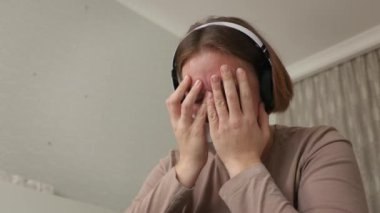 Depresyon. Kulaklıklı, müzik dinleyen ve odasında ağlayan beyaz bir kadının portresi. Alt manzara. Psikoloji ve akıl sağlığı kavramı.