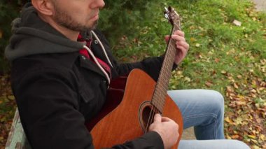 Müzik kağıdından gitar çalan yetişkin, yakışıklı, beyaz bir adam. Bir müzik aleti çalmayı öğrenmek.