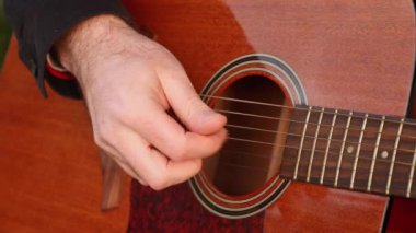 Erkek eli gitar çalma ve parmaklama sicimleri yakın çekim. Bir müzik aleti çalmayı öğrenmek