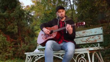 Kafkas asıllı, ciddi, sakallı bir adamın gitar çalarkenki görüntüsü. Bir müzik aleti çalmayı öğrenmek