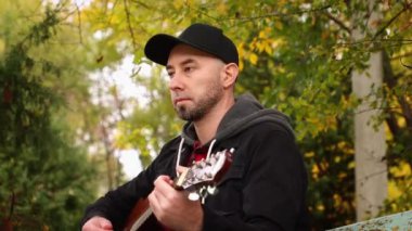 Yetişkin, yakışıklı, beyaz bir adamın gitar çalarken parmaklarıyla başını salladığı bir kare. Bir müzik aleti çalmayı öğrenmek