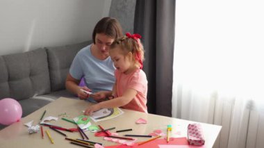 Yetişkin bir Kafkas anne ve küçük bir kızı, kağıt sevgililer günü kartlarını makasla birlikte kesiyorlar. Sevgililer Günü ve Anneler Günü Kutlamaları