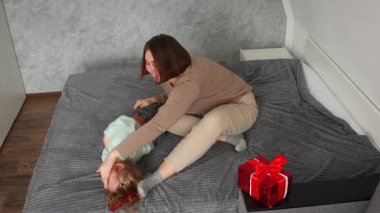 Geniş açılı mutlu anne ve küçük beyaz bir kız yatakta birlikte oynuyorlar. Mutlu aile zamanları. Üst görünüm.