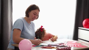 Yetişkin anne ve kızının orta pozu Sevgililer Günü için anneler günü kartlarını süslüyor. Çocuklar için okul öncesi eğitim.