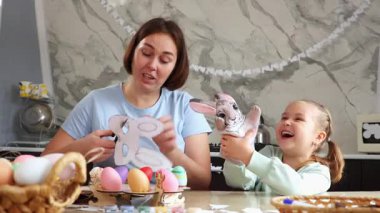Paskalya Baharı. Anne ve küçük kızı birlikte çocuk yaratıcılığı yapıyor. Paskalya süsleri oyan bir kadın ve tavşan eldiveniyle oynayan bir kız. Okul öncesi çocukların eğitimi..