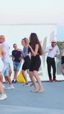 10.08.2024, İbiza, İspanya. Bir grup çok ırklı mutlu kadın dansçı sokakta dans dersinde antrenman yapıyor. Ağır çekim. Spor ve eğlence aktiviteleri. Dikey yönelim.