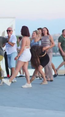 10.08.2024, İbiza, İspanya. Bir grup çok ırklı kadın dansçı sokakta dans dersinde antrenman yapıyor. Ağır çekim. Spor ve eğlence aktiviteleri. Dikey yönelim.