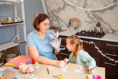 Kafkasyalı anne ve mutlu küçük kızının Paskalya için el işi ve süslemeler yaptığı geniş bir kare.